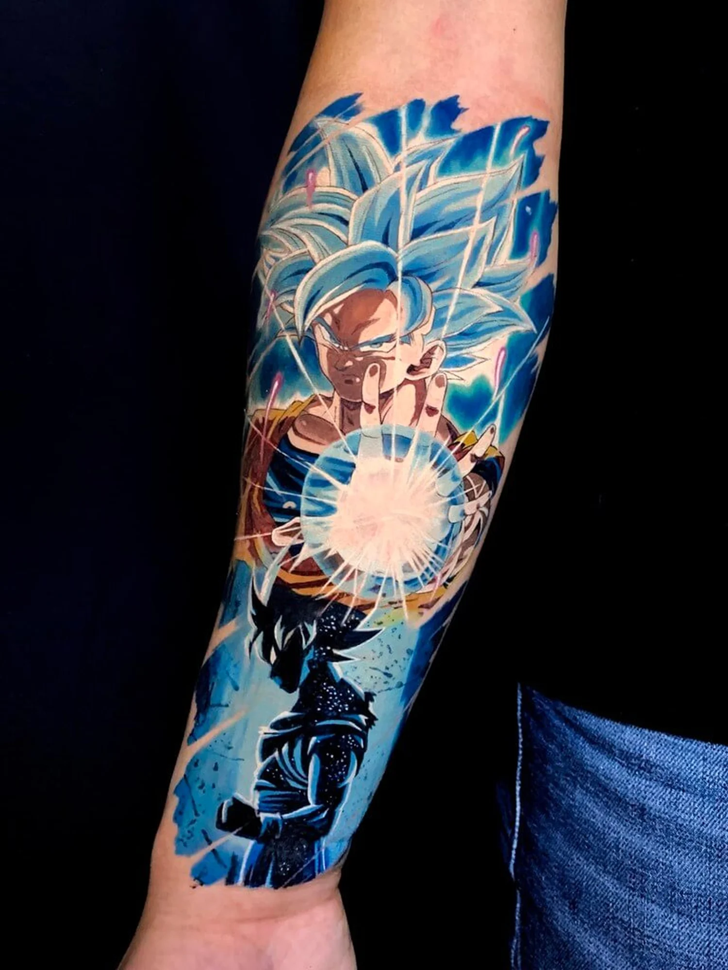 Color anime forearm tattoo of Goku in Super Saiyan Blue form charging a Kamehameha energy blast, inspired by Dragon Ball, by Quang Pham at Qneedle Tattoo Studio