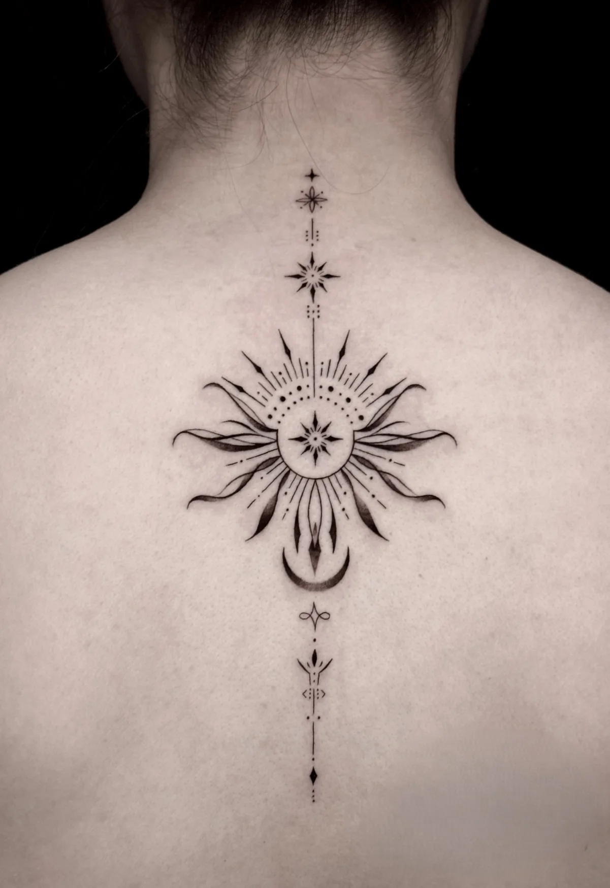 Fine line sun and stars back tattoo at Qneedle Tattoo Studio
