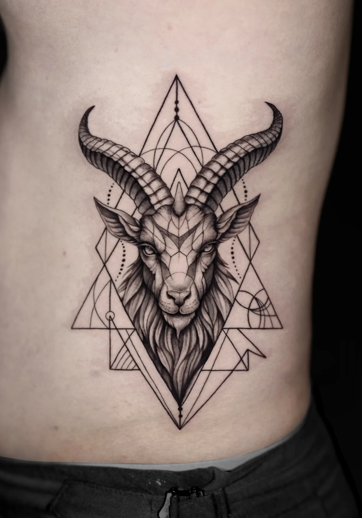 Geometric goat head tattoo with fine linework and blackwork detailing at Qneedle Tattoo Studio