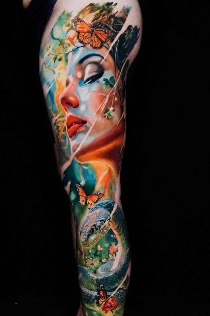 Color fantasy realism full leg tattoo featuring a woman's portrait, butterflies, lush forest scenery and vibrant nature-inspired details at Qneedle Tattoo Studio